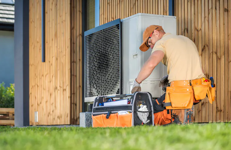 man fitting a heat pump to a home