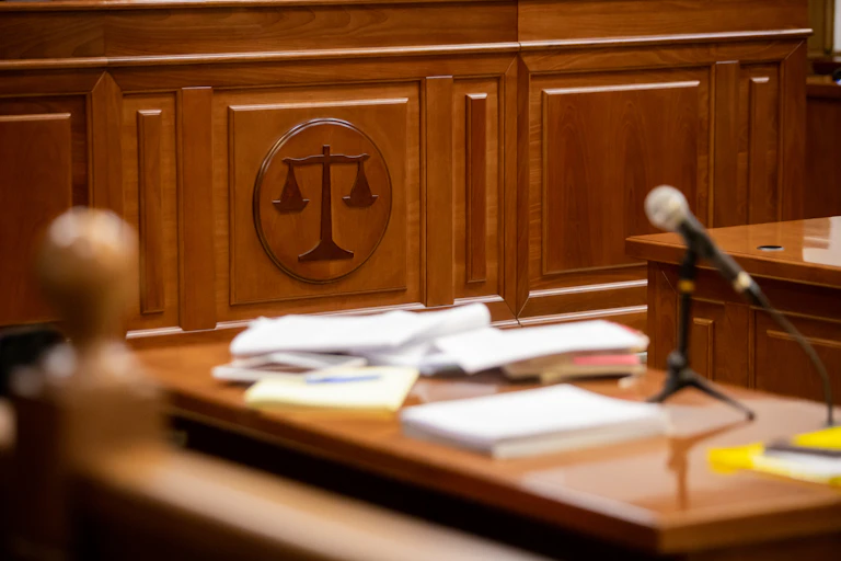 A courtroom with a close up of the scales of justice on a wall