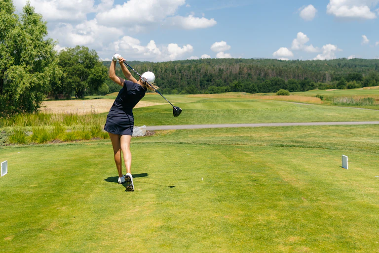 A woman golfer tees off