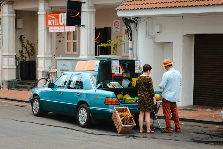 A woman buys durians out the back of a car.