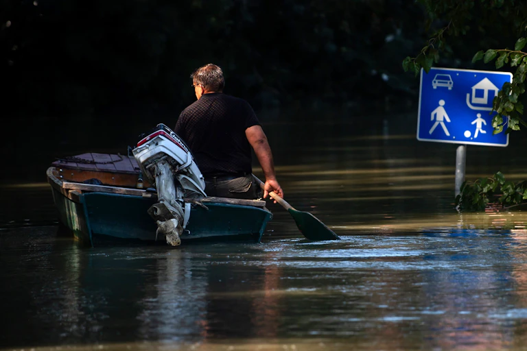 A person paddles in a boat past a traffic sign.