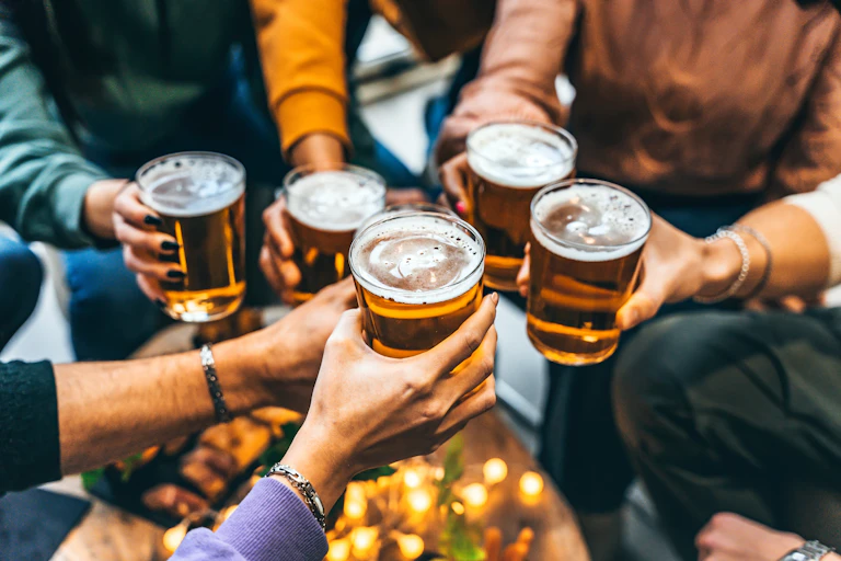 Group of friends drinking and toasting glass of beer at a pub.