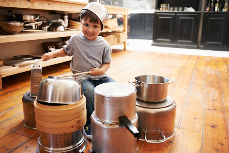 Un niño juega con cacharros de la cocina como si fuesen una batería.