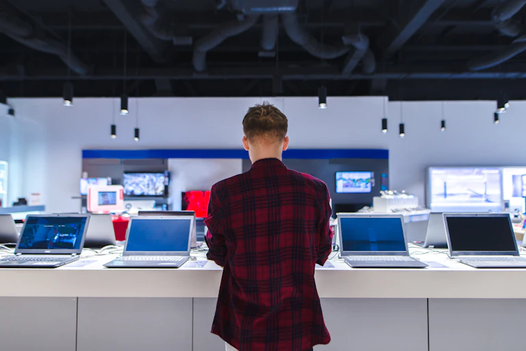 un homme jeune de dos dans un magasin d'informatique