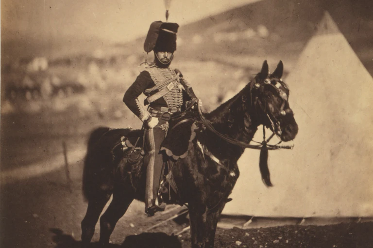 A soldier with tall hat on a horse.