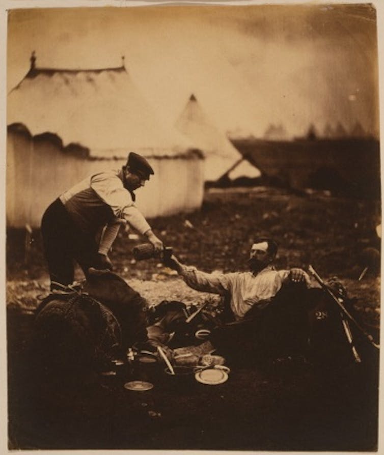 A man reclining while being waited upon.