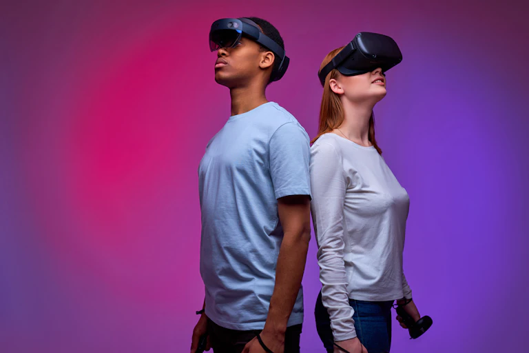 Two people wearing VR headsets against a purple and pink background