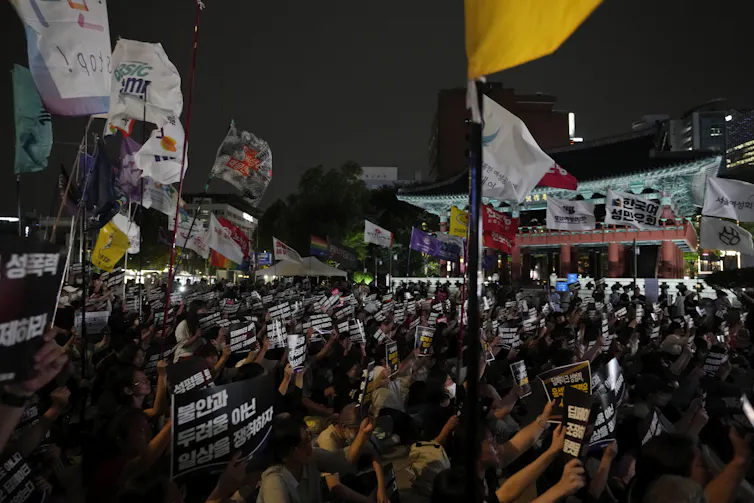 Crowds of activists hold up posters at a rally in Seoul, South Korea, at night.