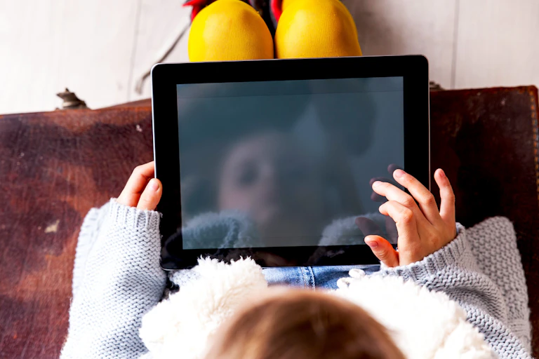 Small child looks at iPad on their lap
