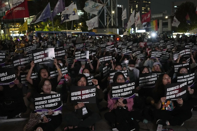 Crowds of activists hold up posters at a rally in Seoul, South Korea, at night.
