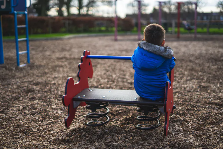 Young boy sitting on his own in a play park.