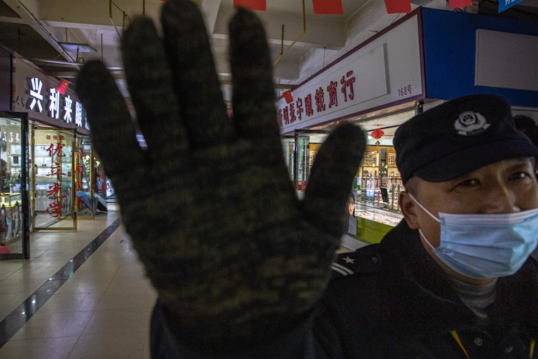 A security guard stops a photographer taking pictures at the Huanan Seafood Wholesale Market in Wuhan, China.