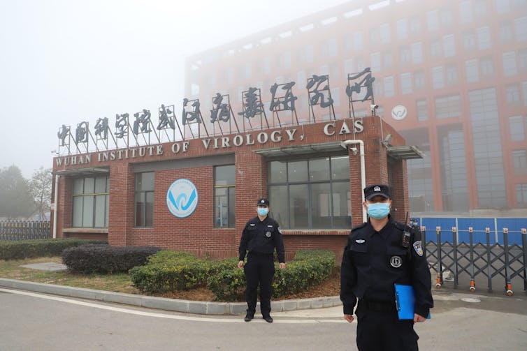 Two masked security guards outside the Wuhan Institute of Virology.