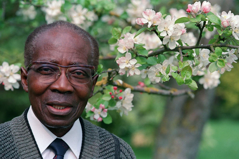 Photo de Léopold Sedar Senghor devant un arbre en fleurs