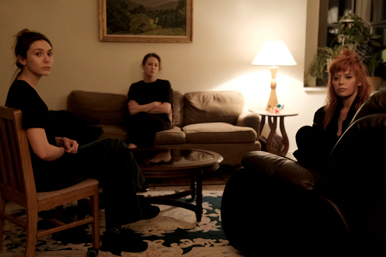 Elizabeth Olsen, Carrie Coon and Natasha Lyonne sit in a living room looking at the camera.