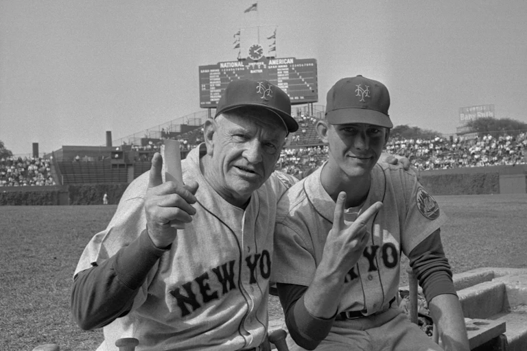 Black and white photo of baseball manager and one of his players sitting in the dugout.