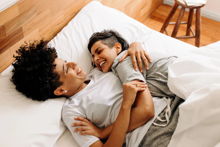 Happy couple cuddling on their bed at home.
