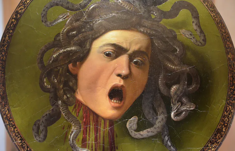 Medusa plasmada en un cuadro circular con la boca abierta en un grito