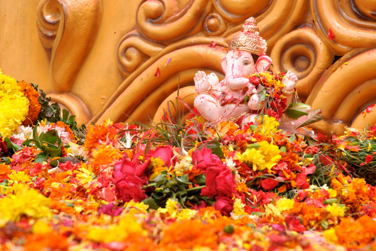 Red and yellow flowers and petals surround an icon of Hindu god Ganesha.