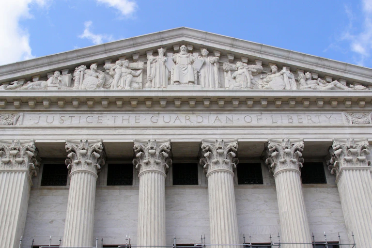 A large gray granite building with words carved onto part of it that say, 'Justice, the Guardian of Liberty.'