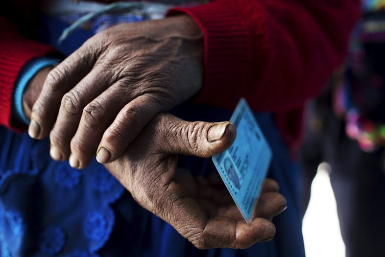 Hands are seen holding a blue identification card.