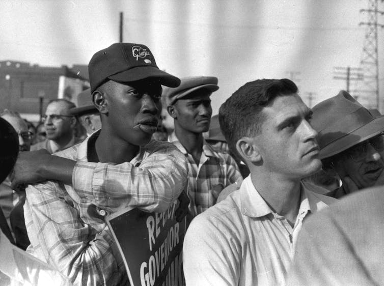 Several man in a crowd listening attentively to someone.