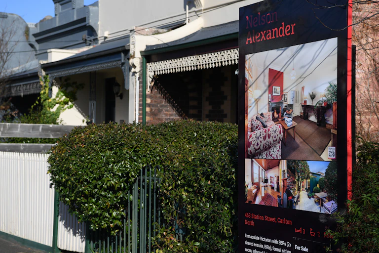 Large sign attached to front fence of single fronted terrace house