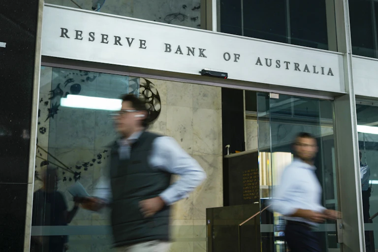 A sign reading reserve bank of australia with people rushing past