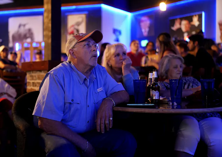Voters watching TV in a bar.
