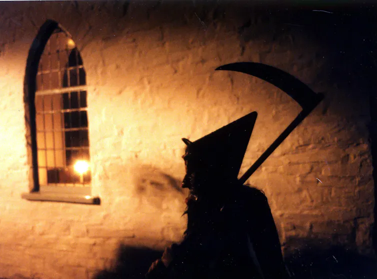 The silhouette of a witch against an old wall.