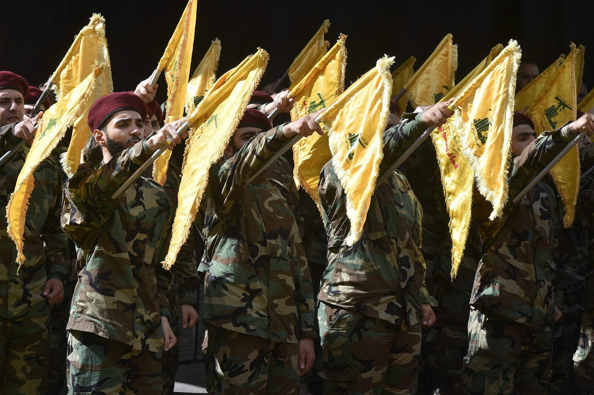 Hezbollah fighters stand at attention with flags at half mast to mourn dead comrades.