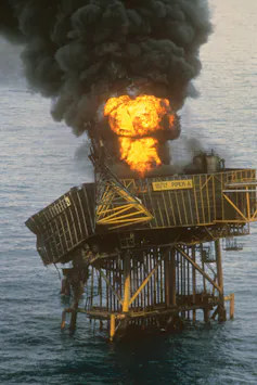 oil rig platform in sea on fire, black smoke