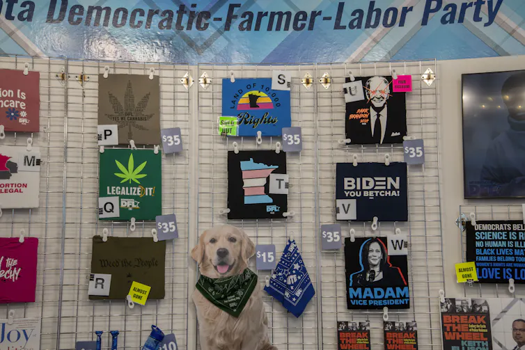 T-shirts are shown on a wall that has the banner 'Democratic-Farmer-Labor Party' and there are numbers next to the different shirts