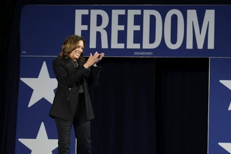 A woman applauds in front of a sign saying 'freedom.'