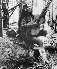 a woman sits and plays a guitar