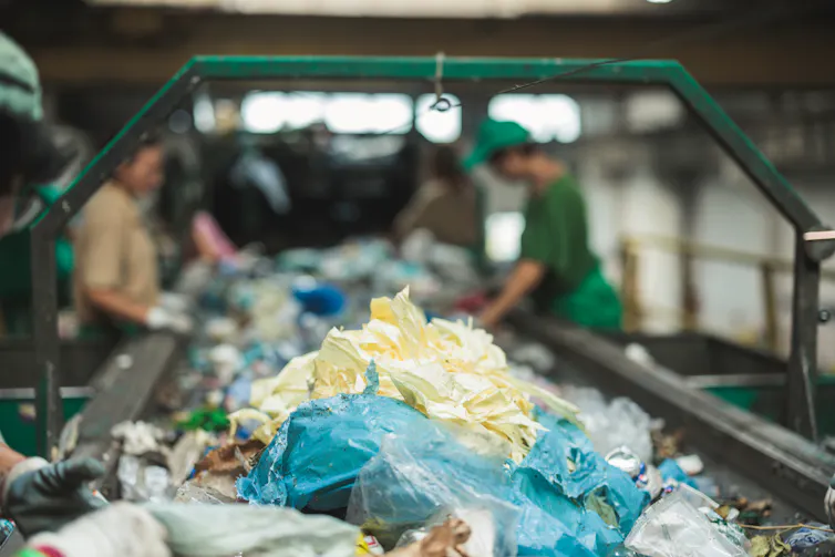 People at a recycling plant sort waste plastics.