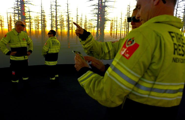 Firefighters in front of a cinema screen featuring a bushfire.