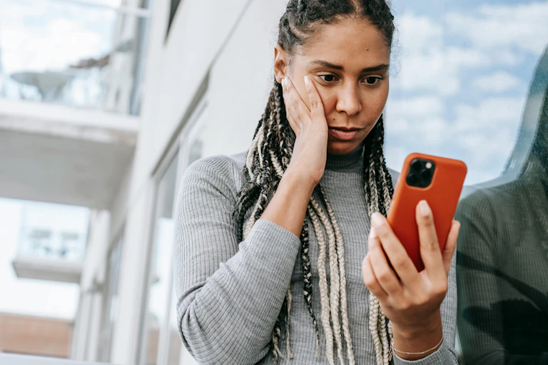 A concerned woman looks at her phone.