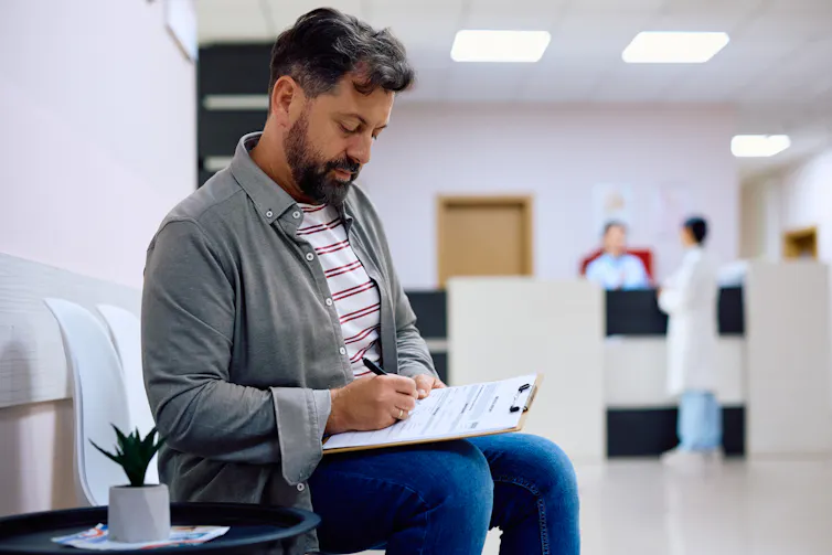 A man filling out a form in a medical waiting room.