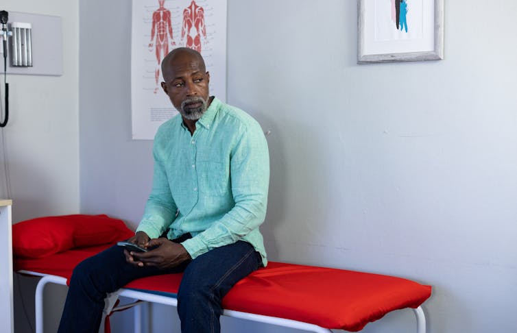 A man sitting on a bed in a doctor's office.