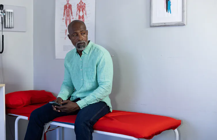 A man sitting on a bed in a doctor's office.