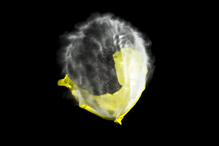 high-speed photo of a yellow balloon in the process of popping