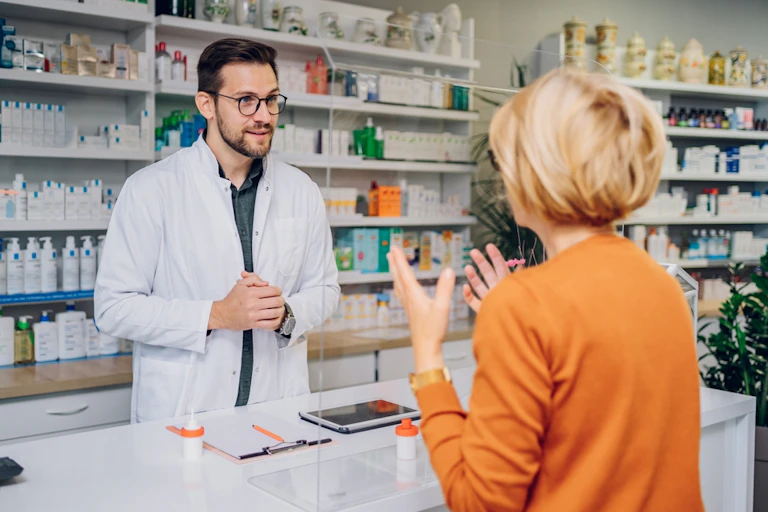 Woman at pharmacy counter talking to male pharmacist
