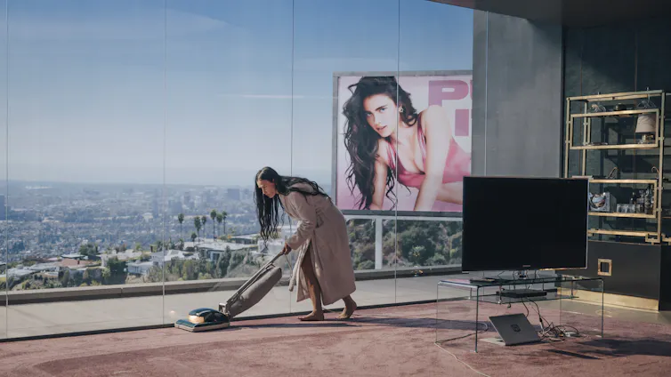 Elisabeth vacuums, Sue is on a billboard.