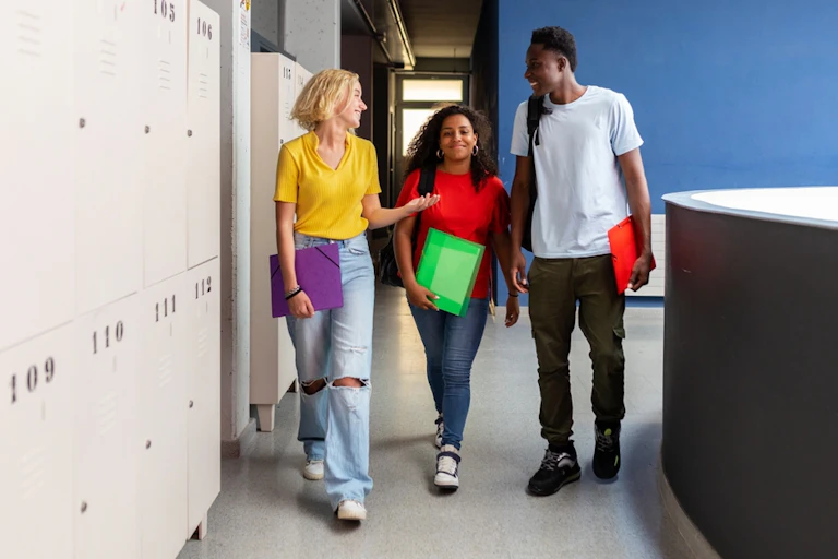Three young people talking to each other as they walk past some lockers