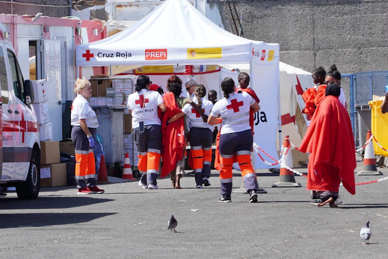 Migrantes se acercan a una carpa acompañados por miembros de la Cruz Roja