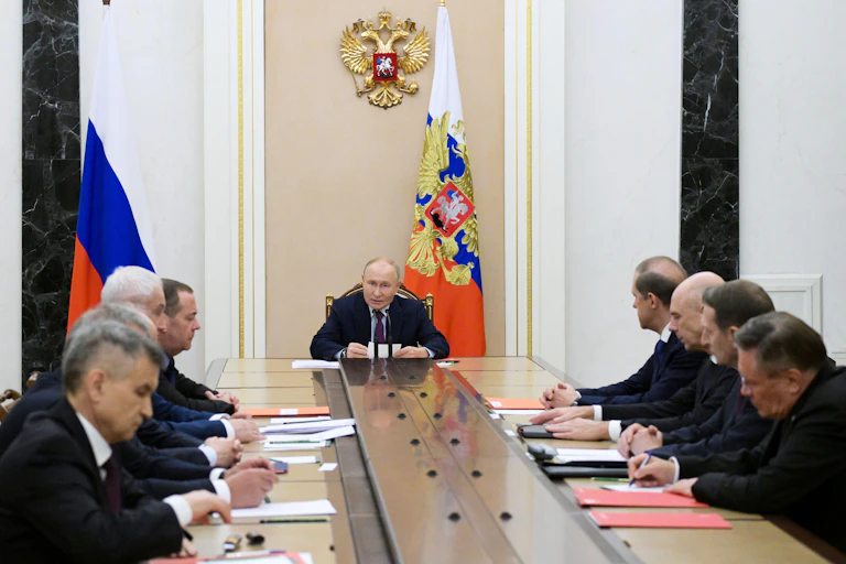 Russian president Vladimir Putin sits at the end of a long table in his Kremlin office, speaking to members of his security council.