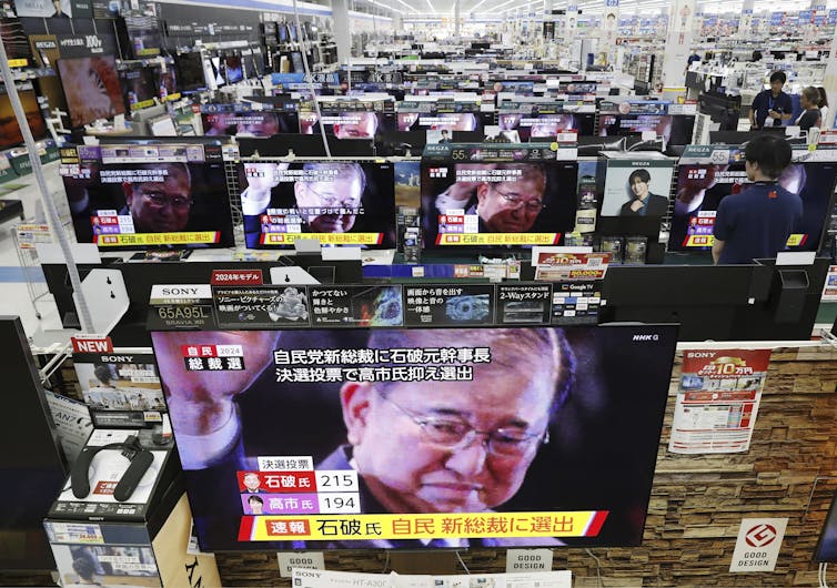 Rows of TV screens showing the Japanese election result.