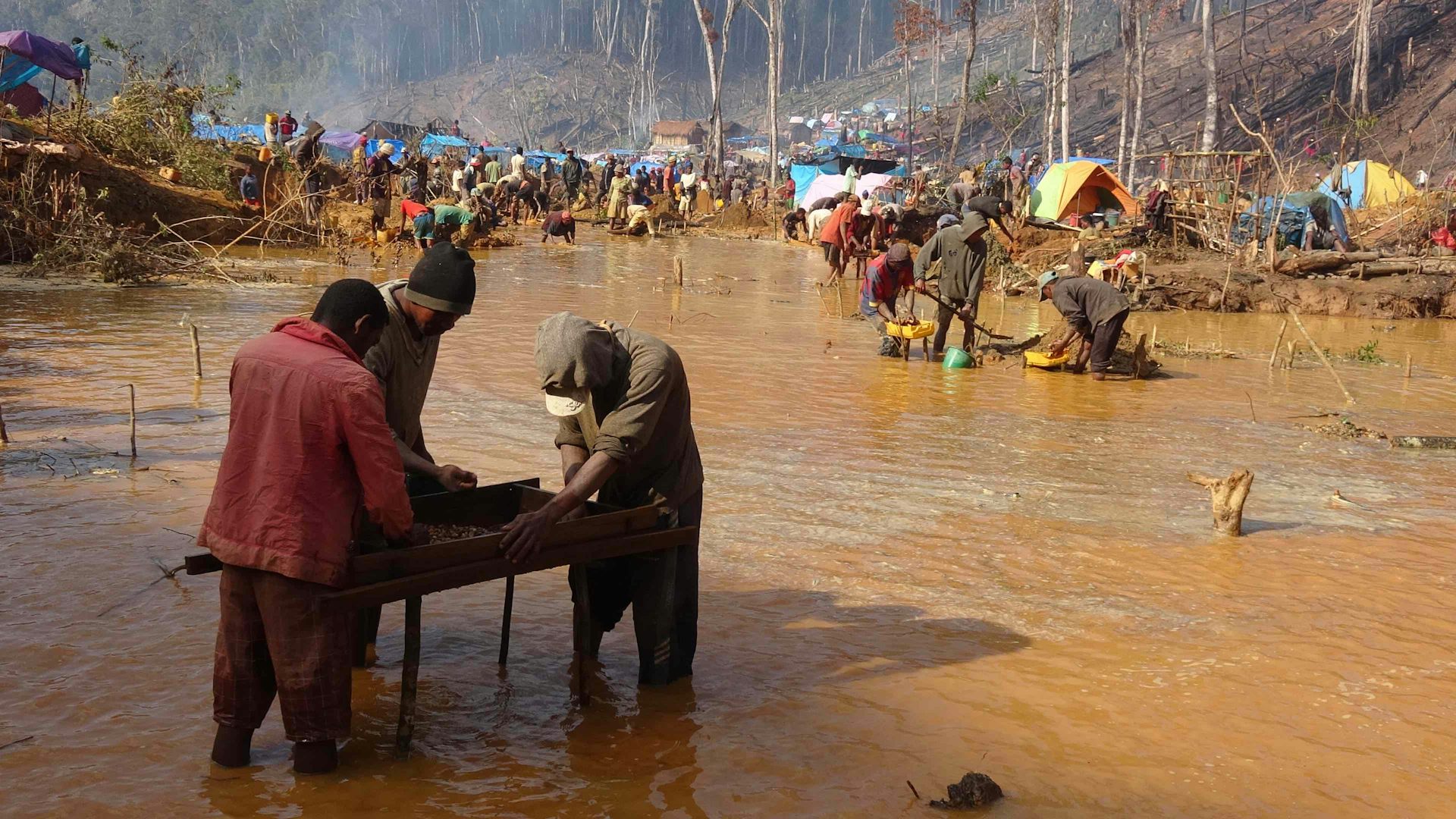 three miners sieving for sapphires, brown river in background