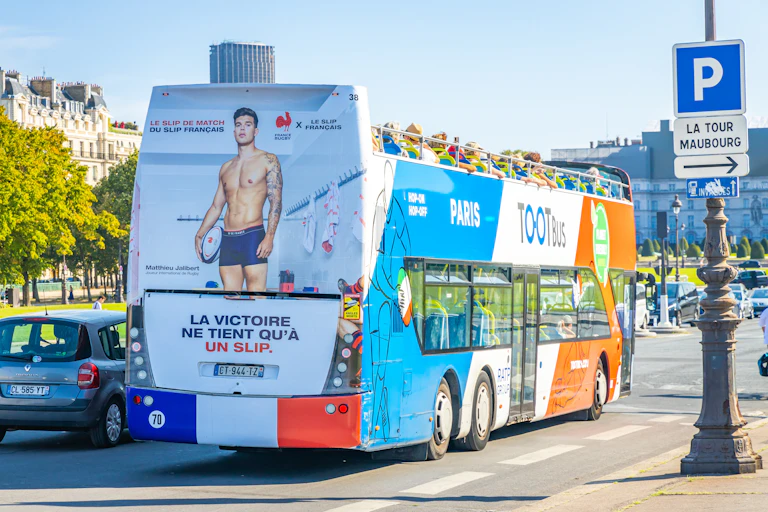 Un bus avec une publicité pour le slip français au dos. Le bus est sur l'esplanade des invalides